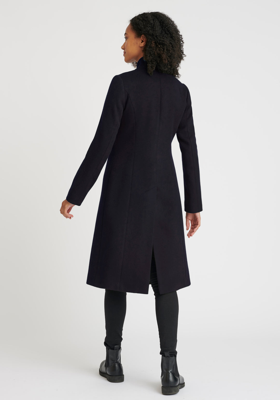 A model wears the Opera coat, a fitted, longline coat made from thick navy merino wool.