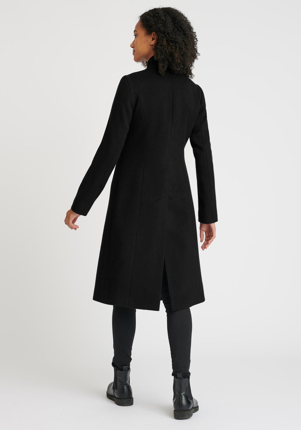 A model wears the Opera coat, a fitted, longline coat made from Italian black wool cashmere, finished with black suede trim.