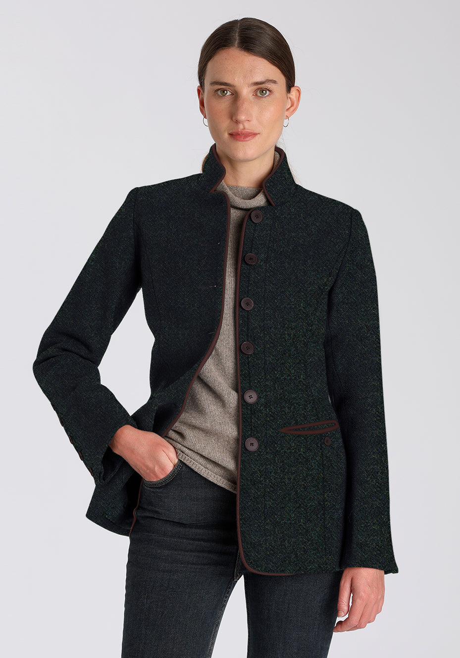 Woman wearing a dark green jacket with brown buttons on a light gray background