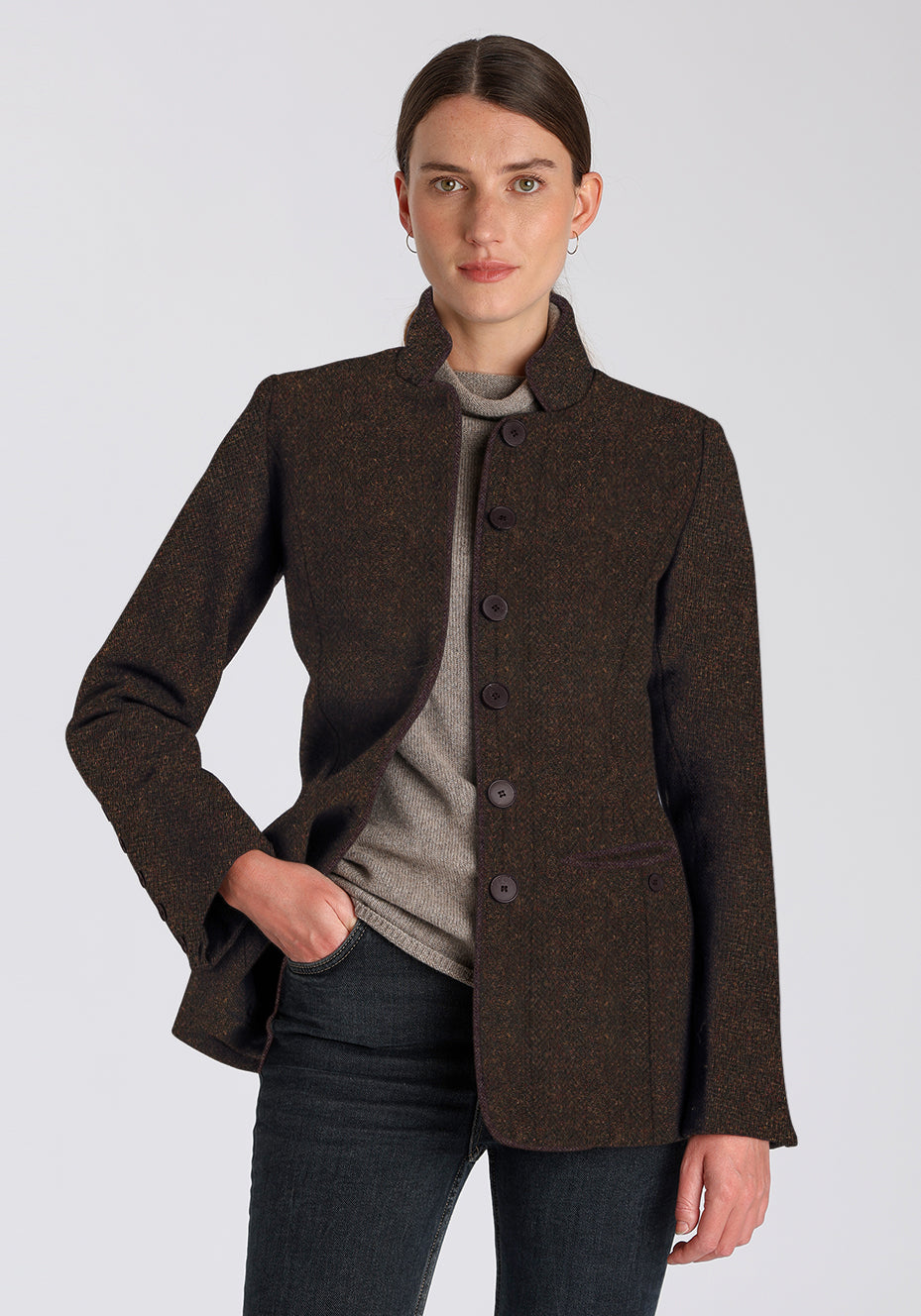 Woman wearing a dark brown jacket with brown buttons on a light gray background