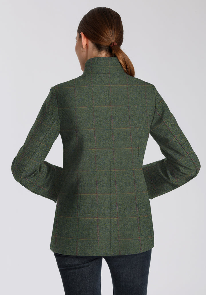 Back of woman wearing a green wool jacket with a yellow and red check on a plain background