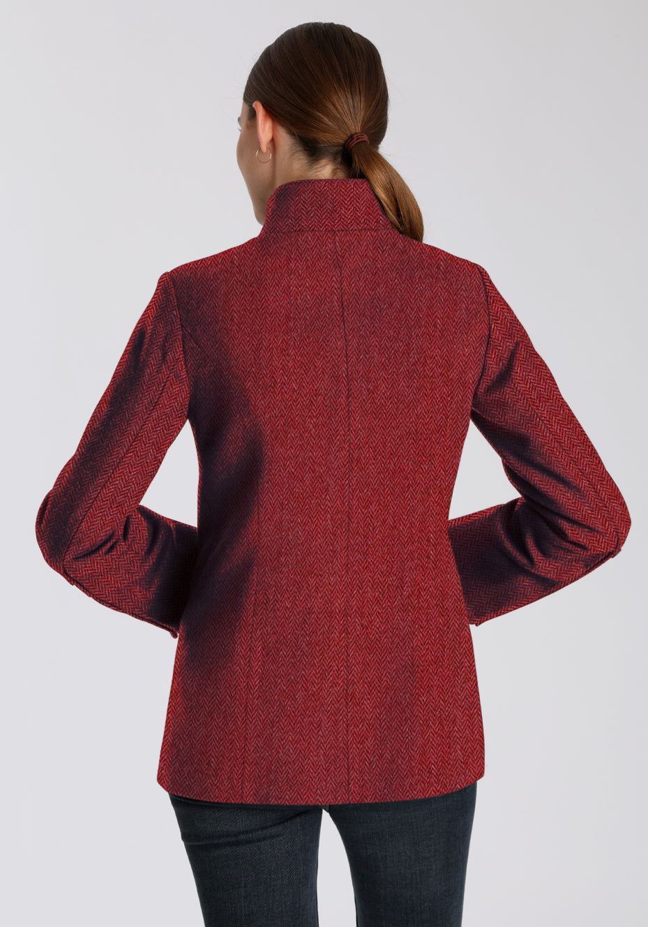 Woman wearing a red herringbone textured jacket on a plain background