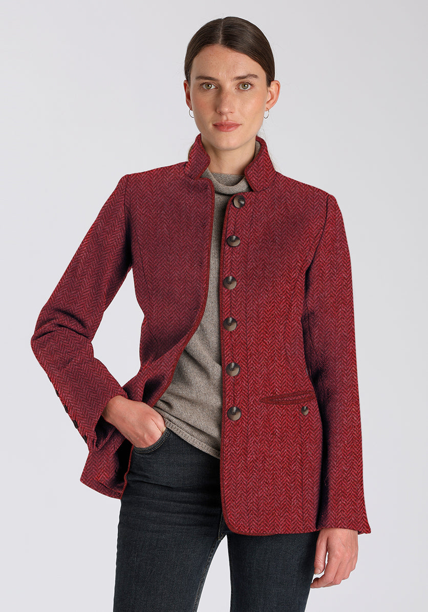 Woman wearing a red herringbone textured jacket with buttons down the middle on a plain background