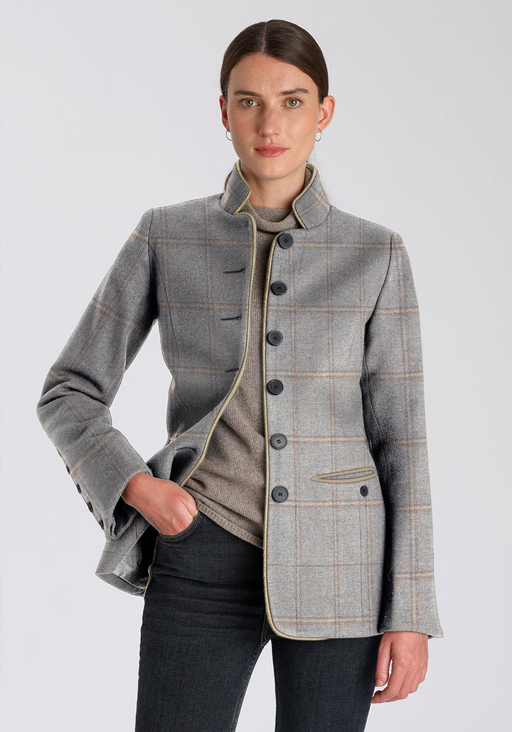 Woman wearing a dove blue and cream checked jacket with black buttons down the middle