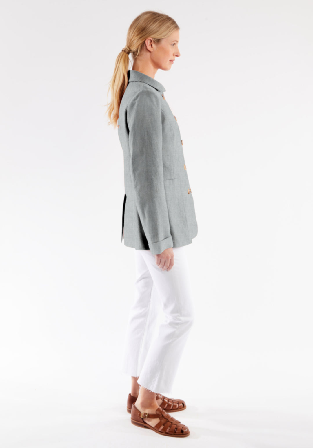 Woman wearing a gray jacket and white pants on a white background