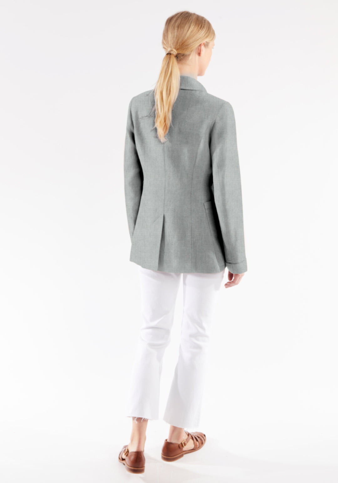 Woman wearing a gray jacket and white pants on a white background
