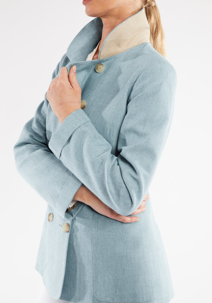 Woman wearing light blue jacket with double breasted buttons. Sand suede under collar detailing