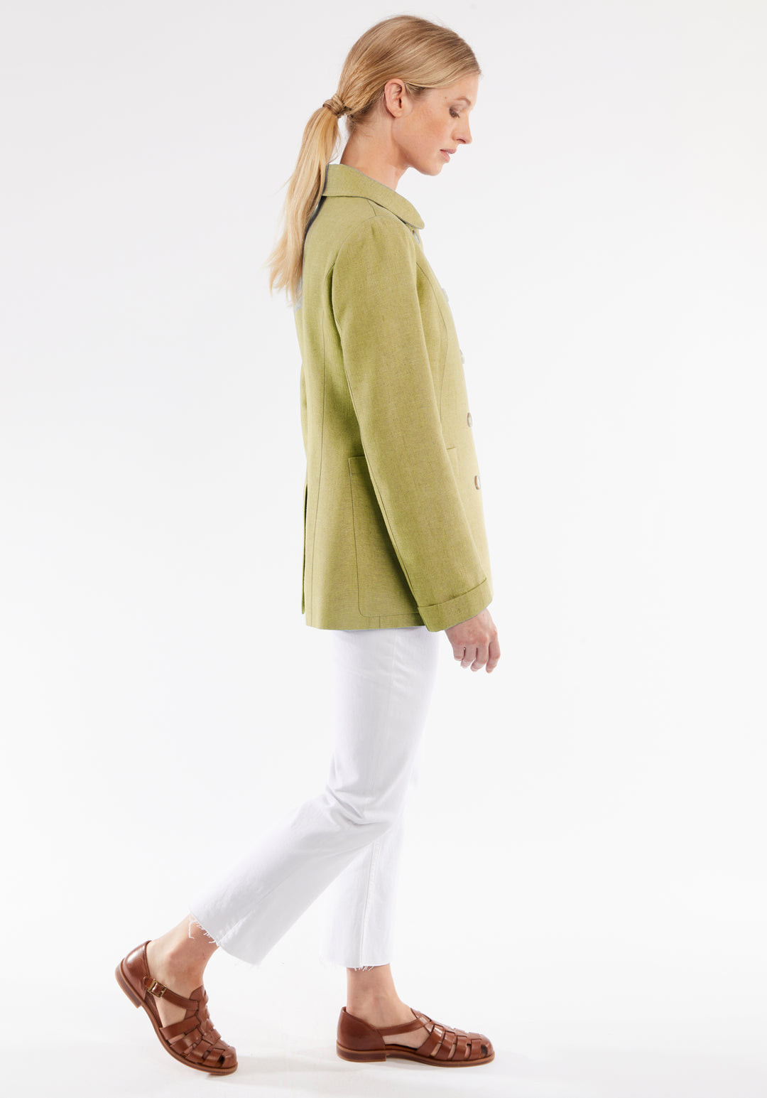 Woman wearing a green jacket and white pants on a white background