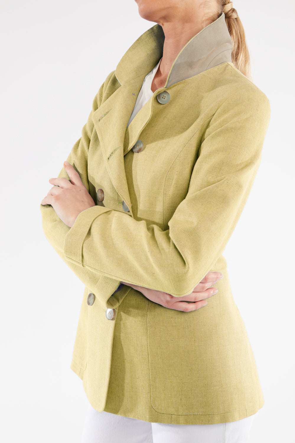 Woman wearing a light green jacket with button details on a white background