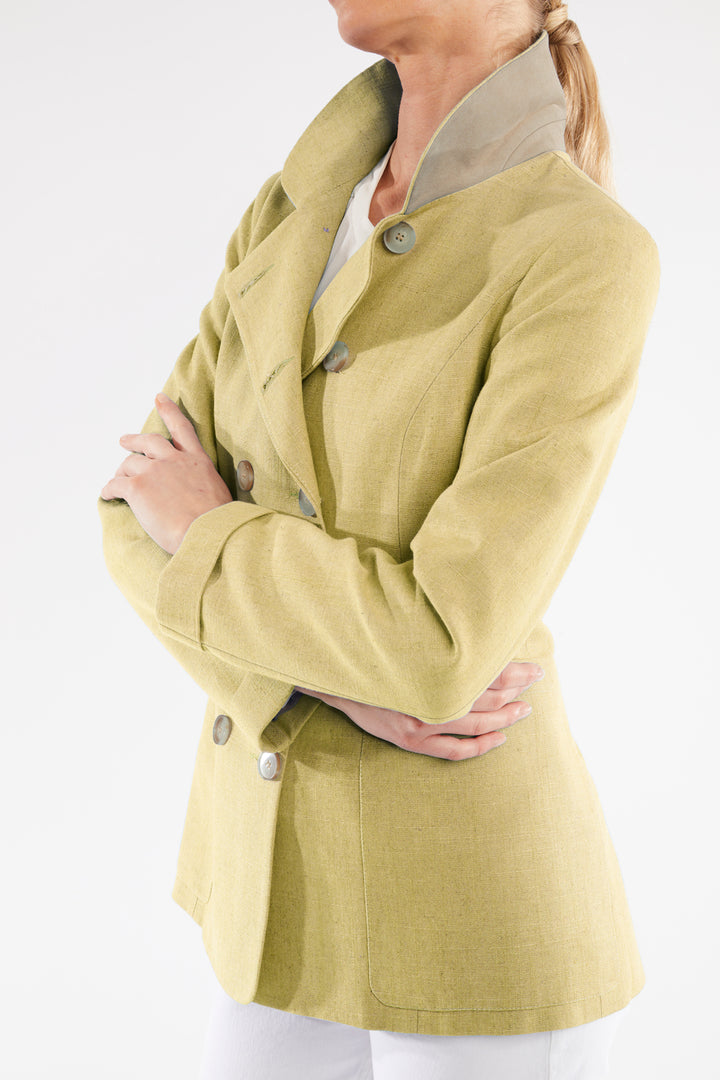 Woman wearing a light green jacket with button details on a white background