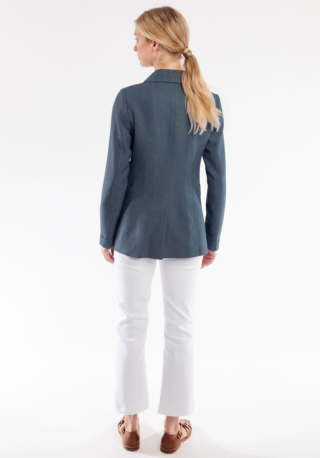 Woman wearing a blue jacket and white pants on a white background