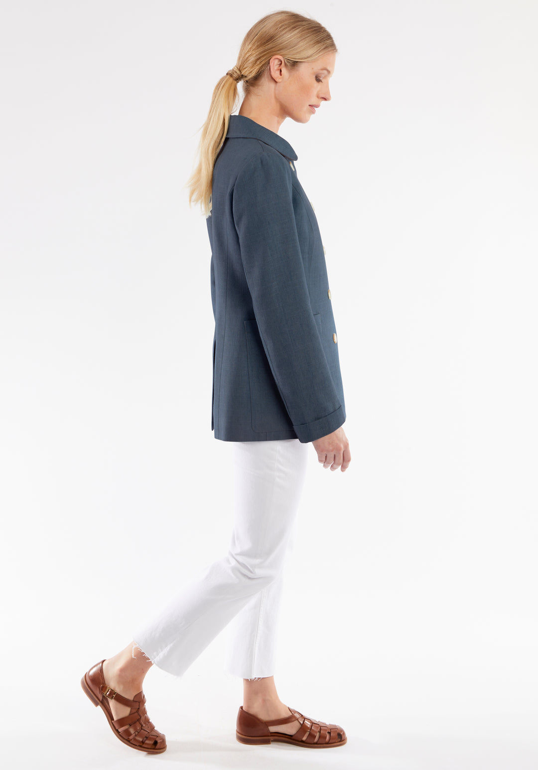 Woman wearing a blue jacket and white pants on a white background