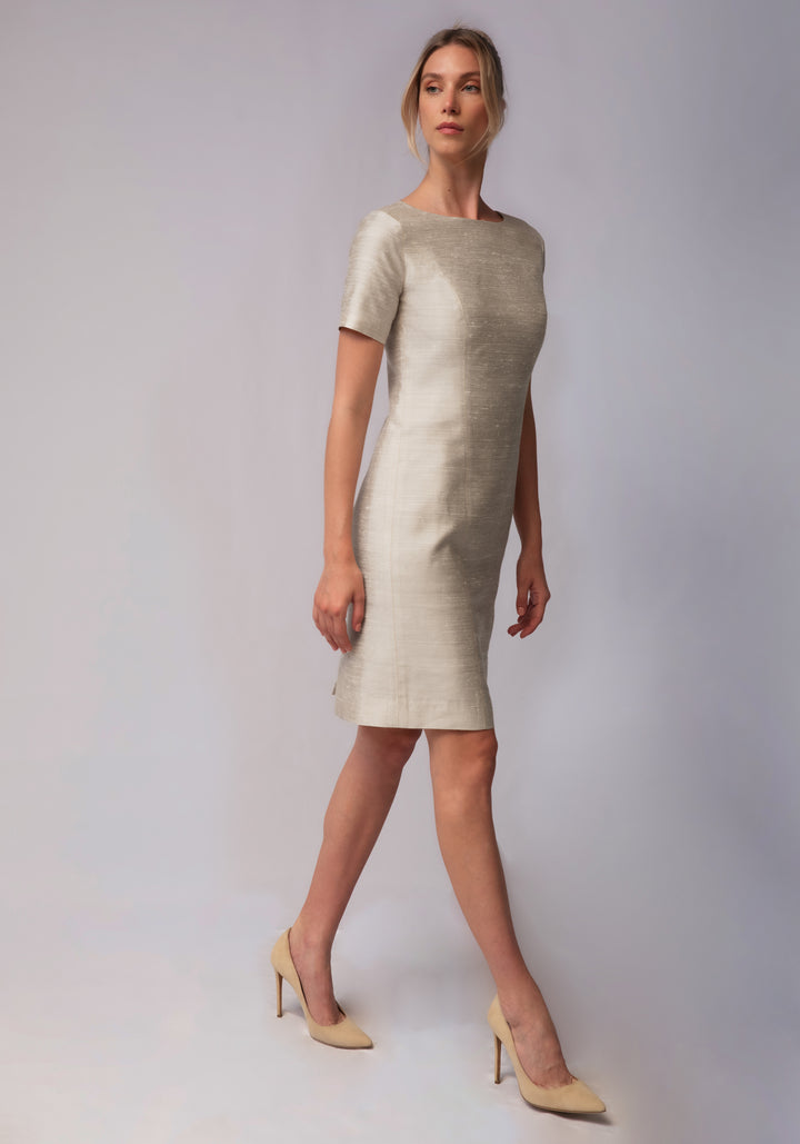 Woman wearing a light-colored dress against a plain background