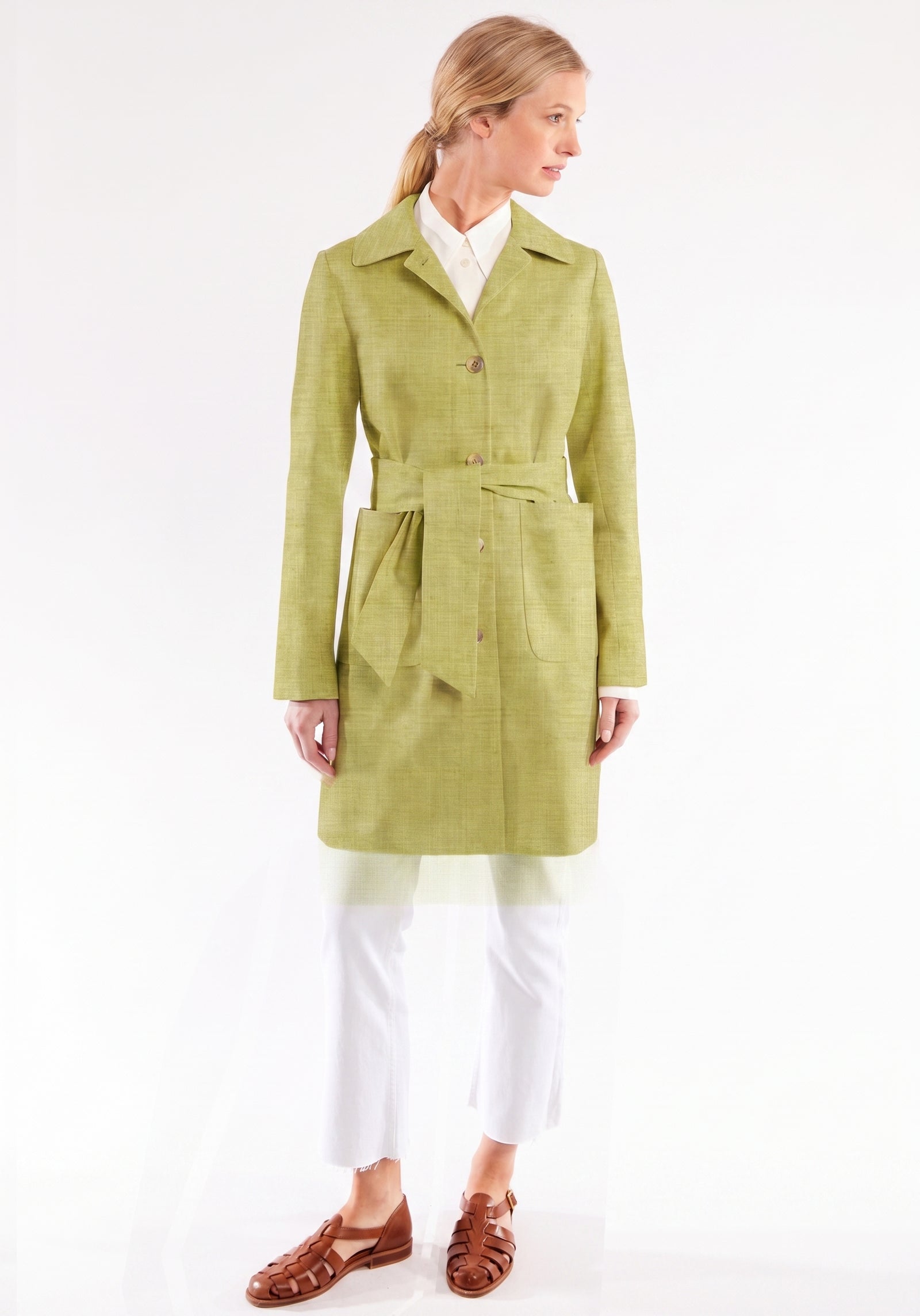 Woman wearing a chartreuse coat on a white background