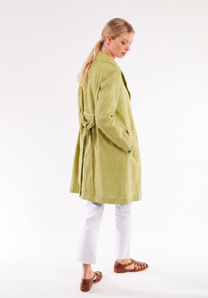 Woman wearing a chartreuse coat on a white background