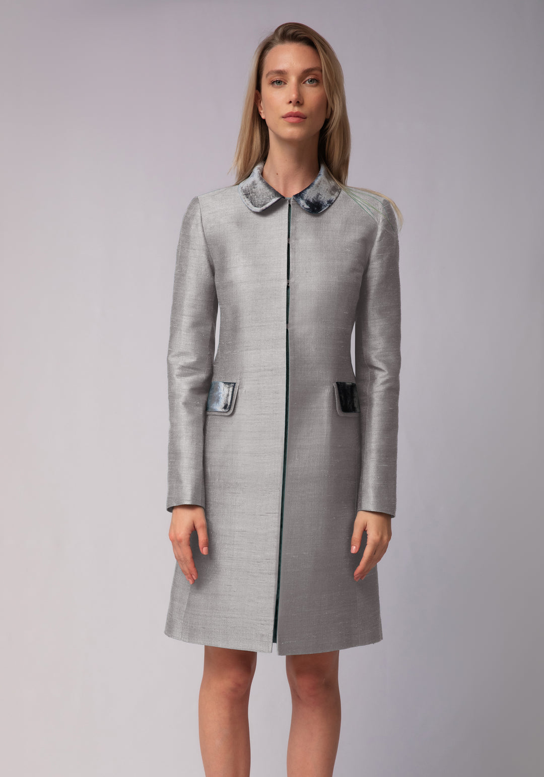 Woman wearing a gray coat with a silver collar on a gray background