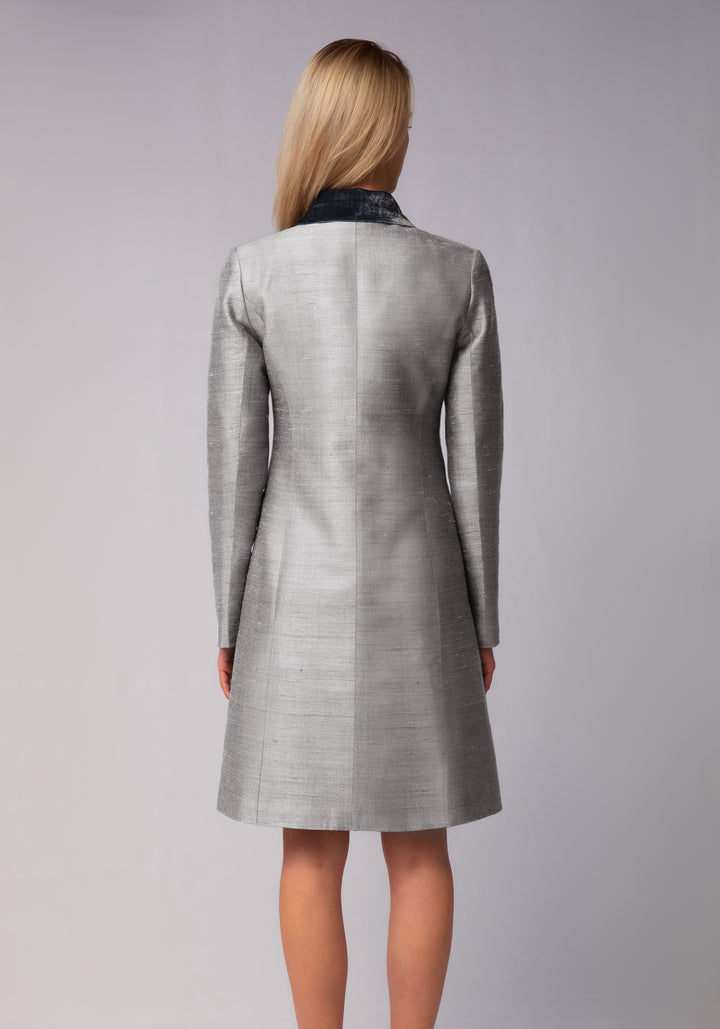 Woman wearing a gray coat with a silver collar on a gray background