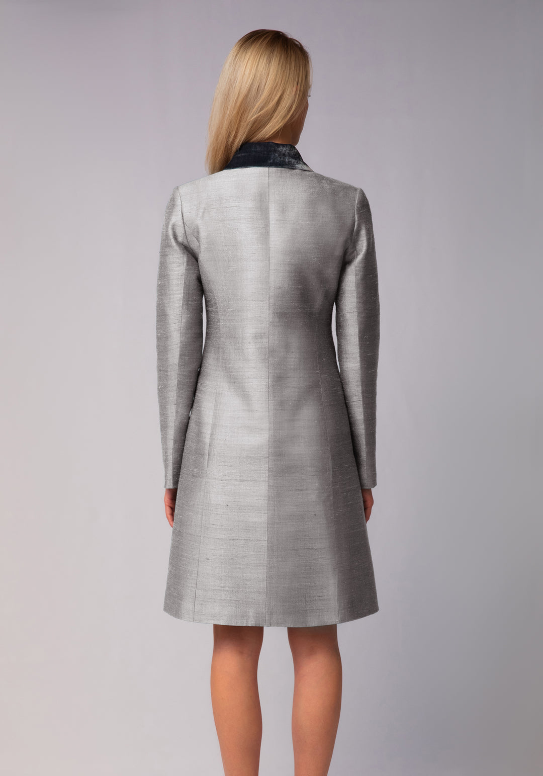 Woman wearing a gray coat with a silver collar on a gray background