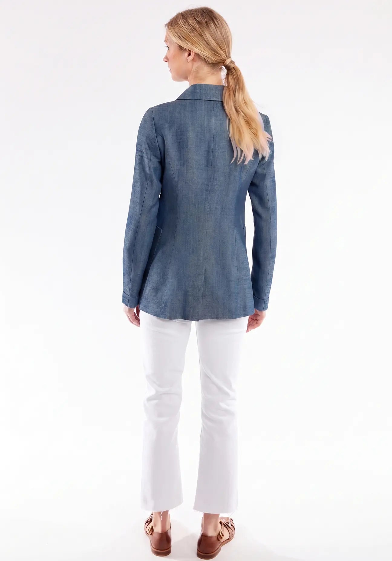 Woman wearing a blue jacket and white pants on a white background