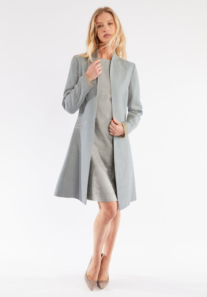 Woman wearing a light gray coat over a dress on a white background