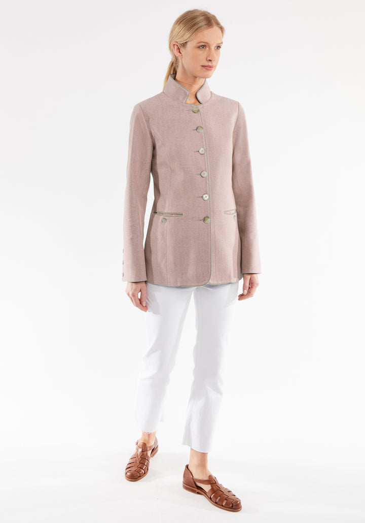 Woman wearing a light pink jacket and white pants on a white background