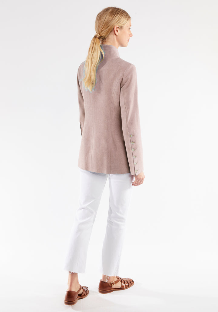 Woman wearing a light pink jacket and white pants on a white background
