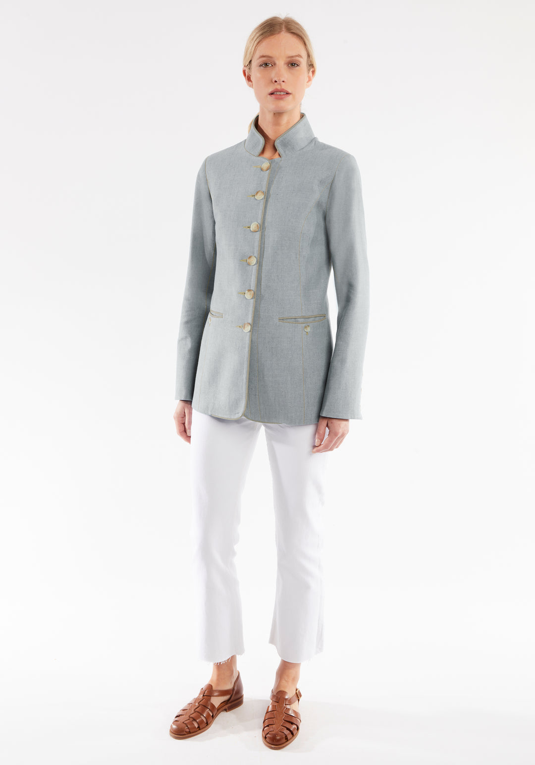 Woman wearing a gray jacket with ivory buttons on a white background
