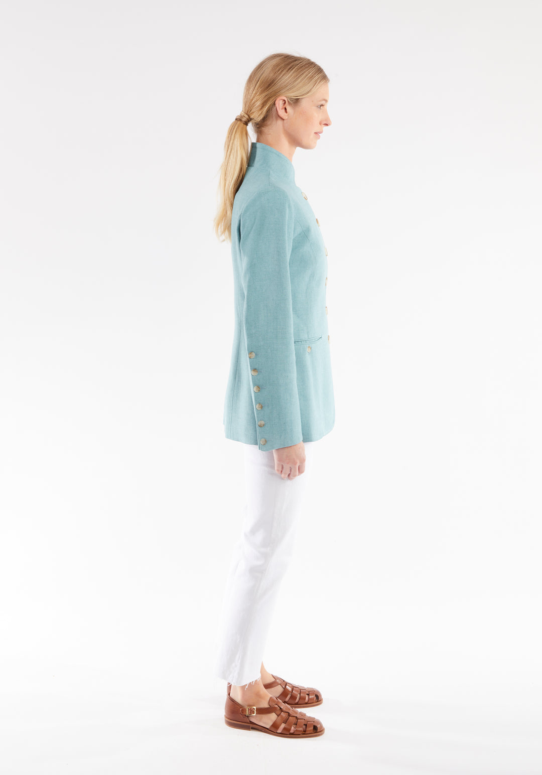 Side view of woman wearing light blue linen jacket with buttons down the sleeve