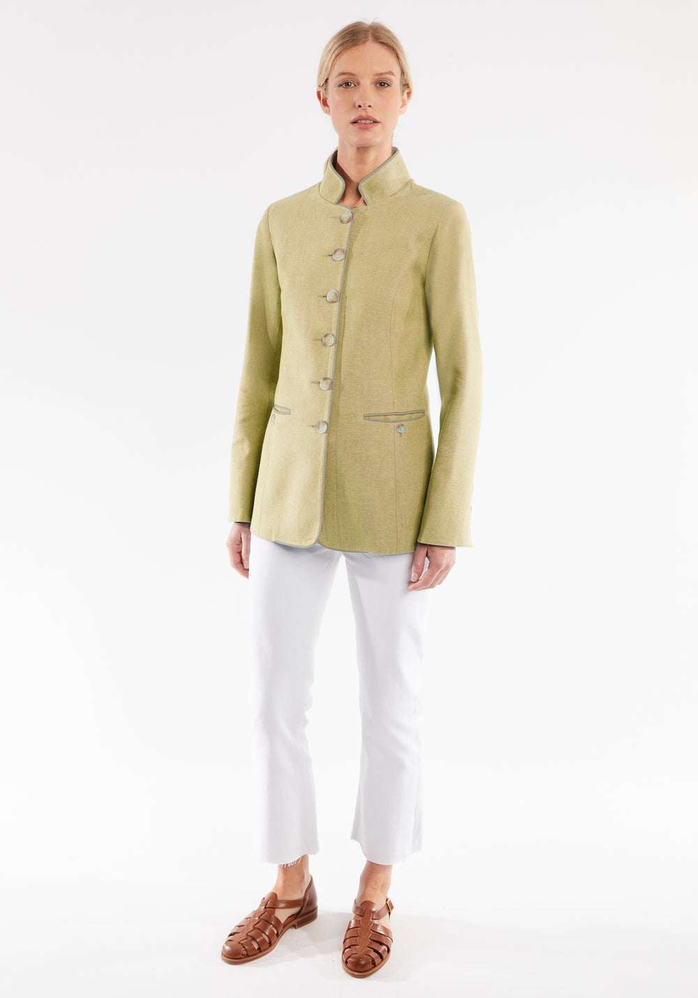 Woman wearing a light green jacket with white pants on a white background