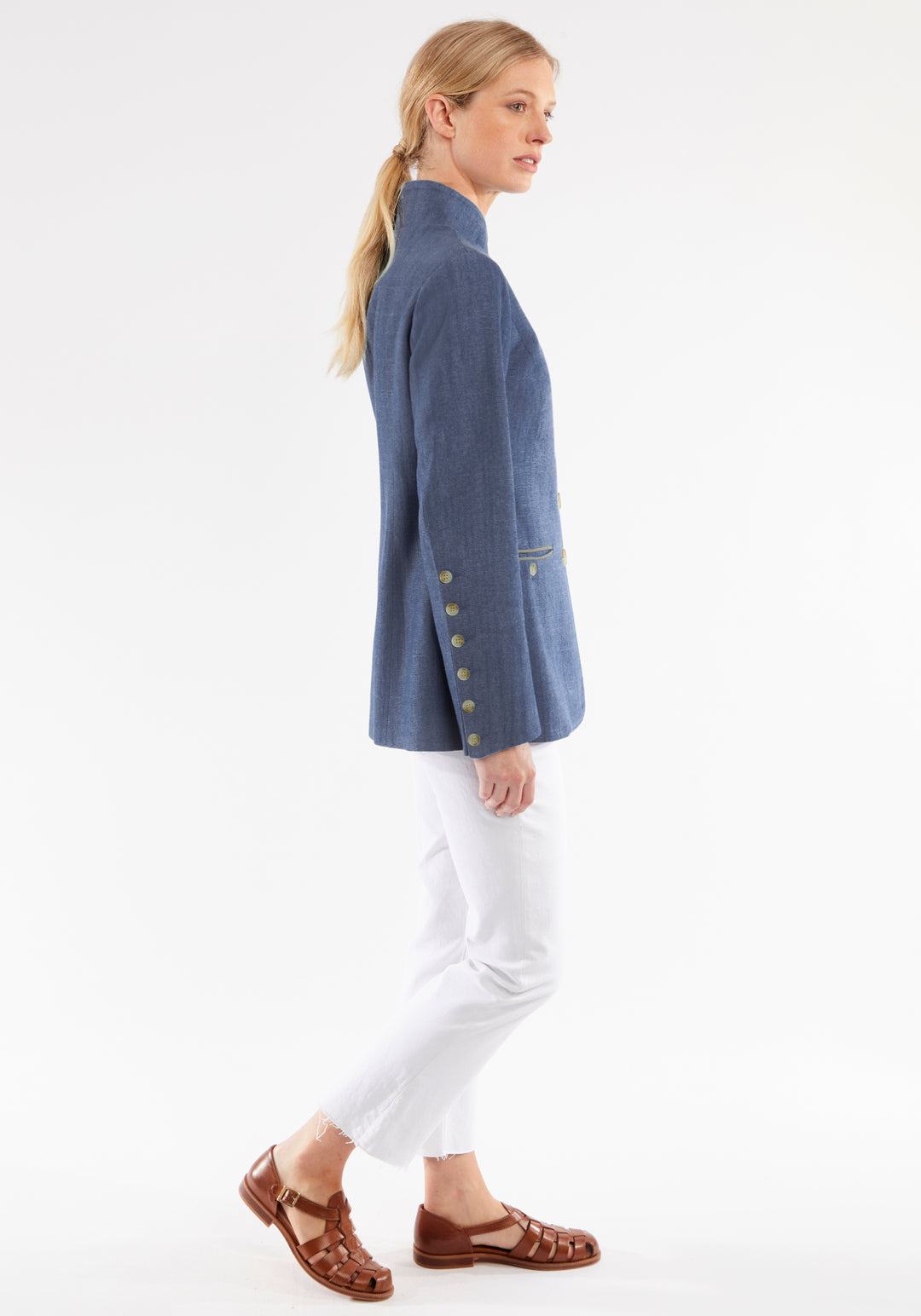Woman wearing a blue jacket with button details on a white background