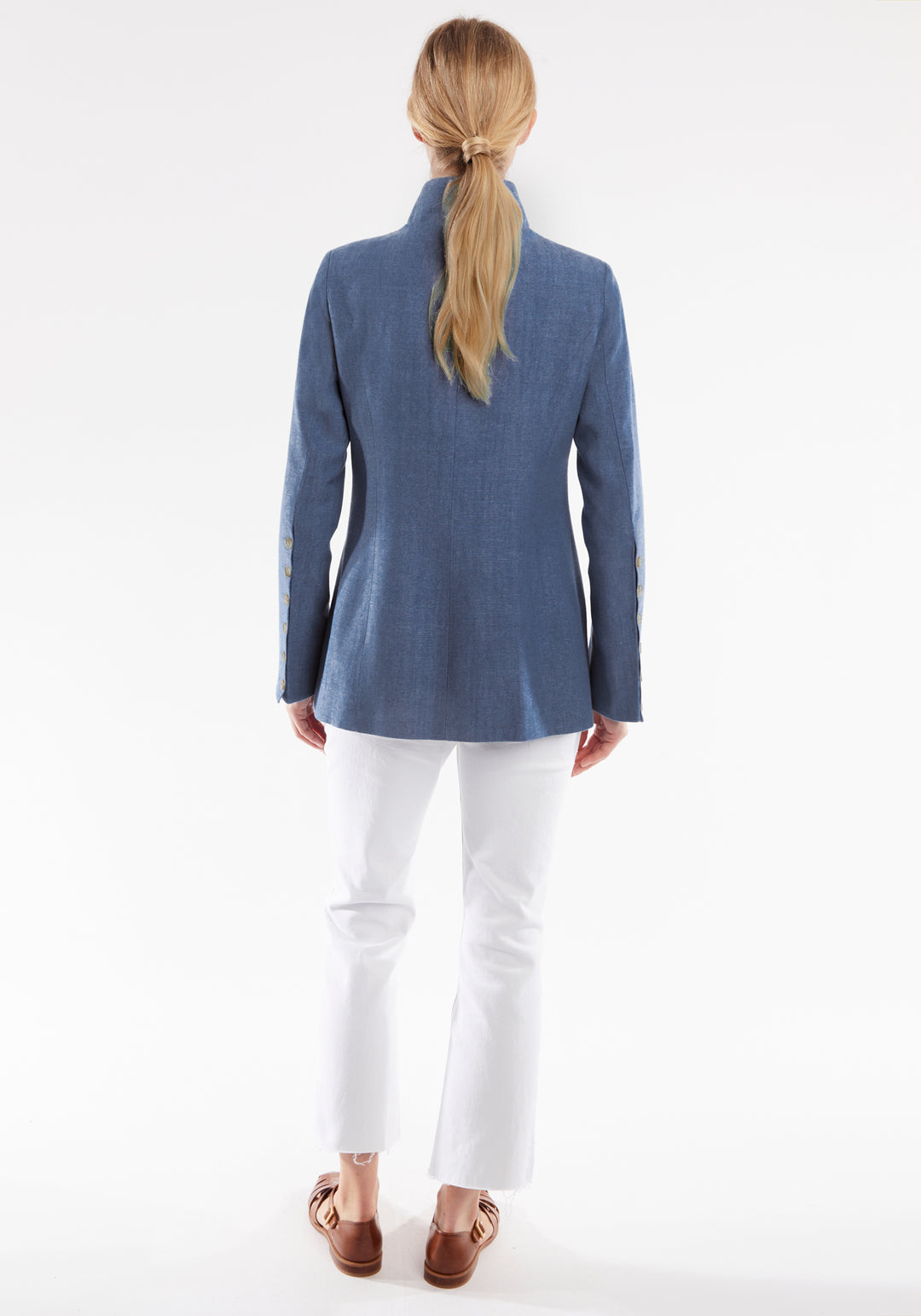 Person wearing a blue jacket and white pants on a white background