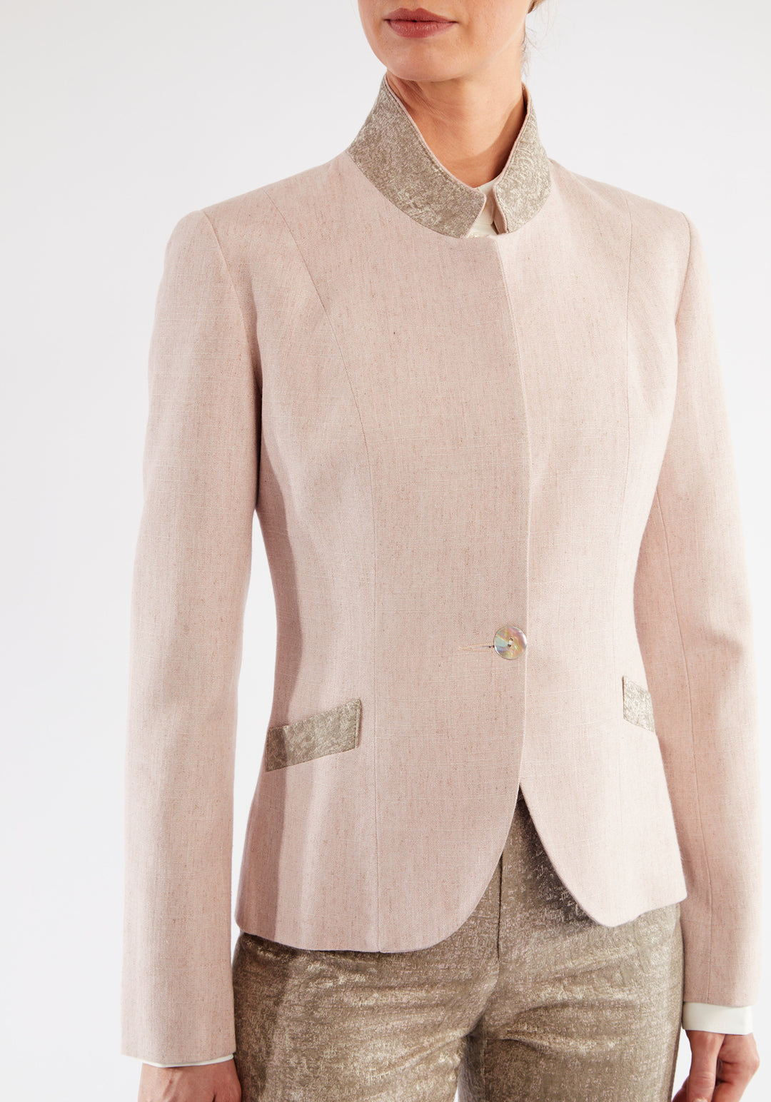 Woman wearing light pink jacket with beige pocket and collar detailing