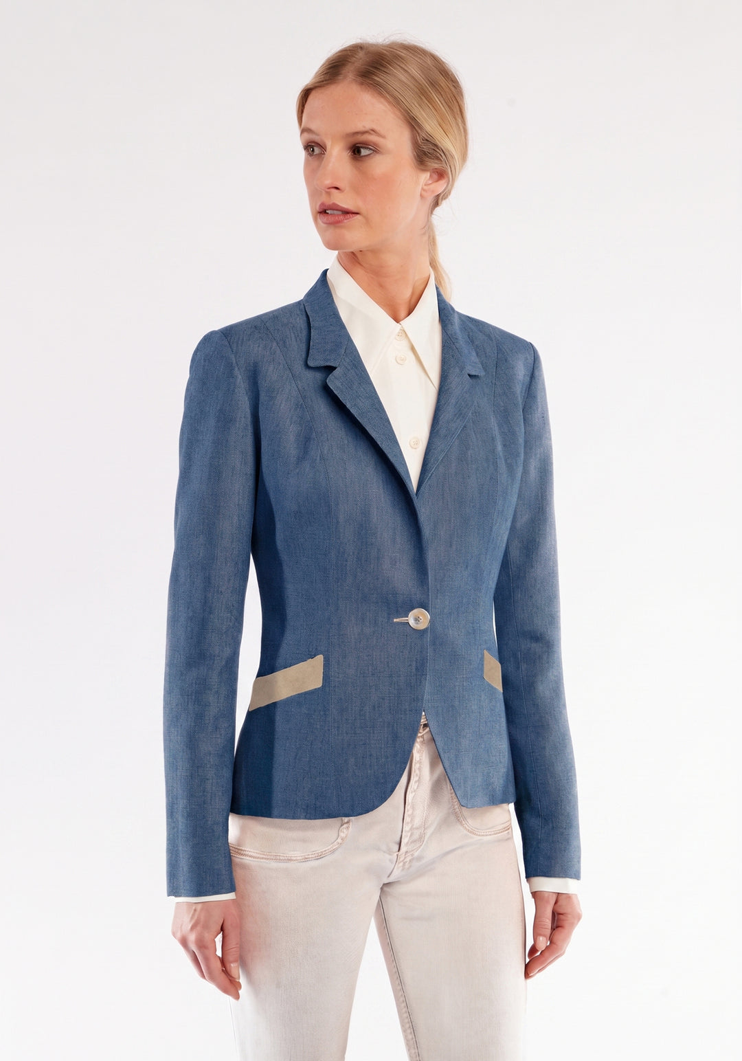 Woman wearing a blue jacket with a white shirt and pants on a light gray background