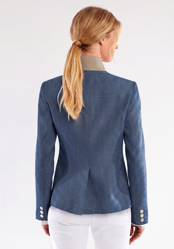 Woman wearing a blue jacket with white pants on a plain background