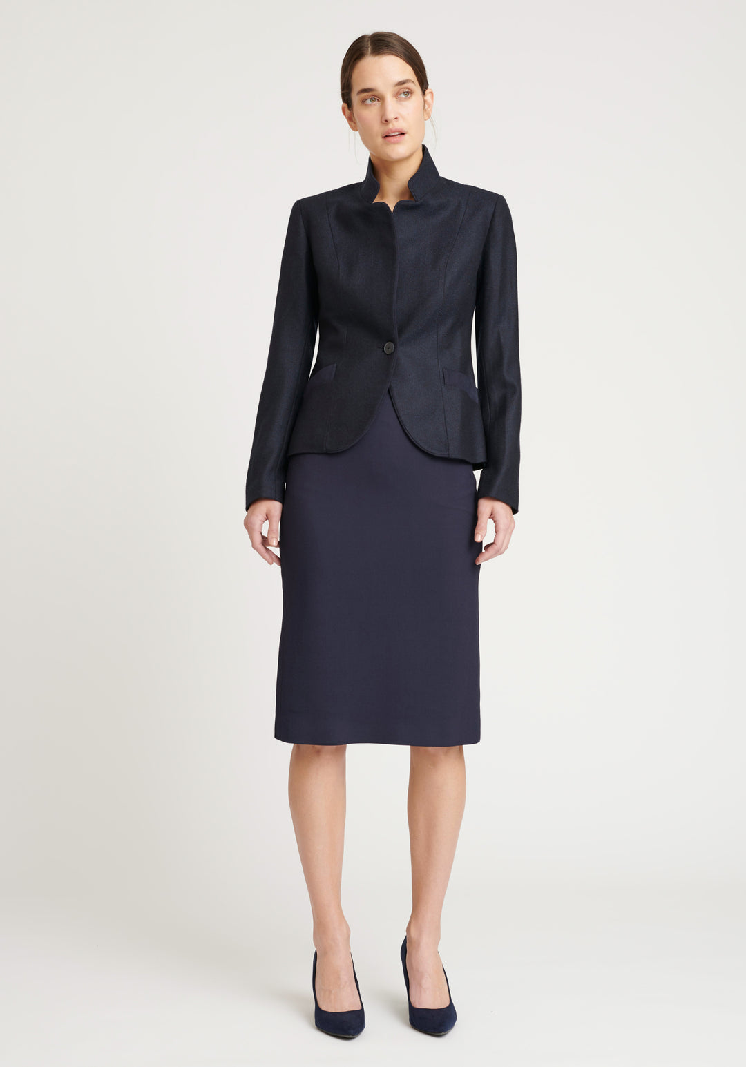 A model wears the Tallulah jacket in a smart navy and black herringbone lambswool. It has a sleek, tailored look, with a single button fastening and suede trimmed collar that can be worn up or down.