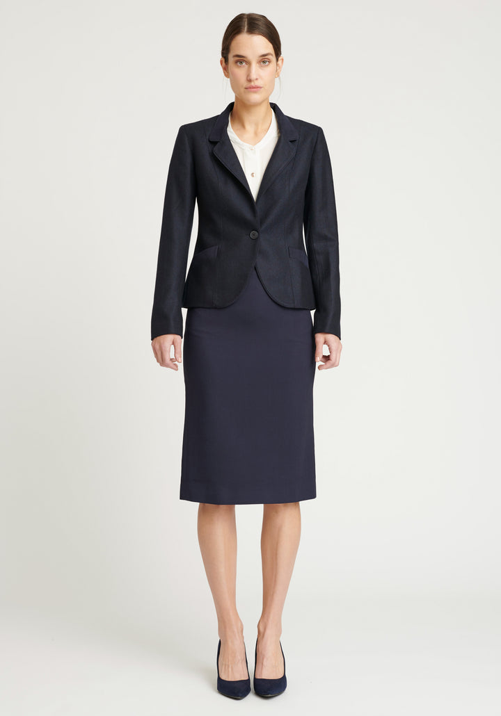 A model wears the Tallulah jacket in a smart navy and black herringbone lambswool. It has a sleek, tailored look, with a single button fastening and suede trimmed collar that can be worn up or down.