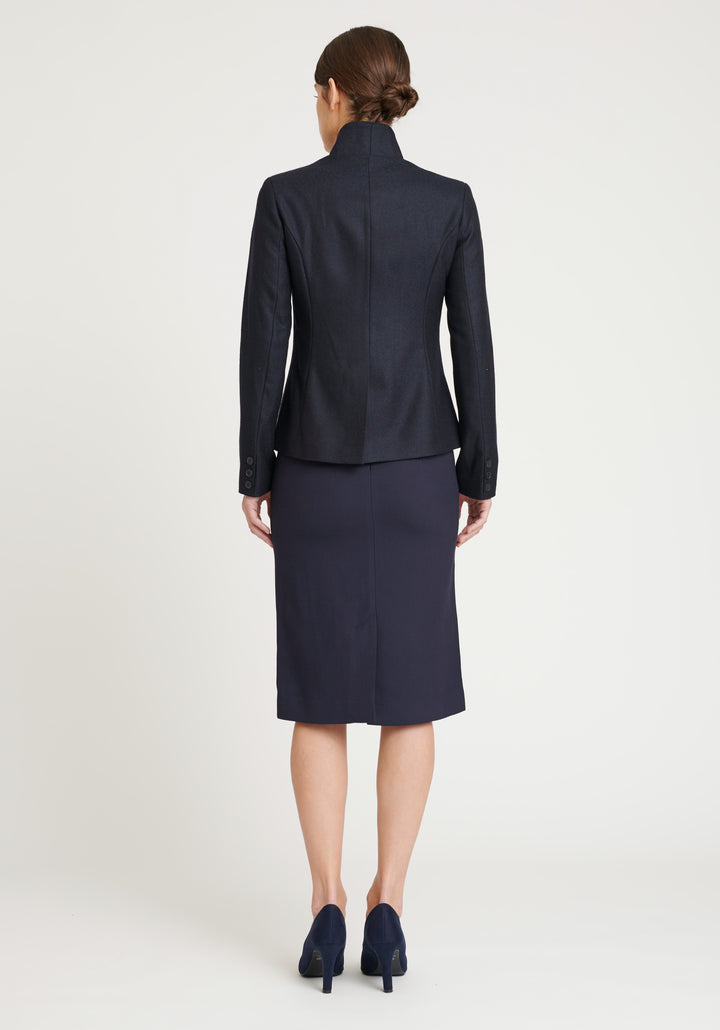 A model wears the Tallulah jacket in a smart navy and black herringbone lambswool. It has a sleek, tailored look, with a single button fastening and suede trimmed collar that can be worn up or down.