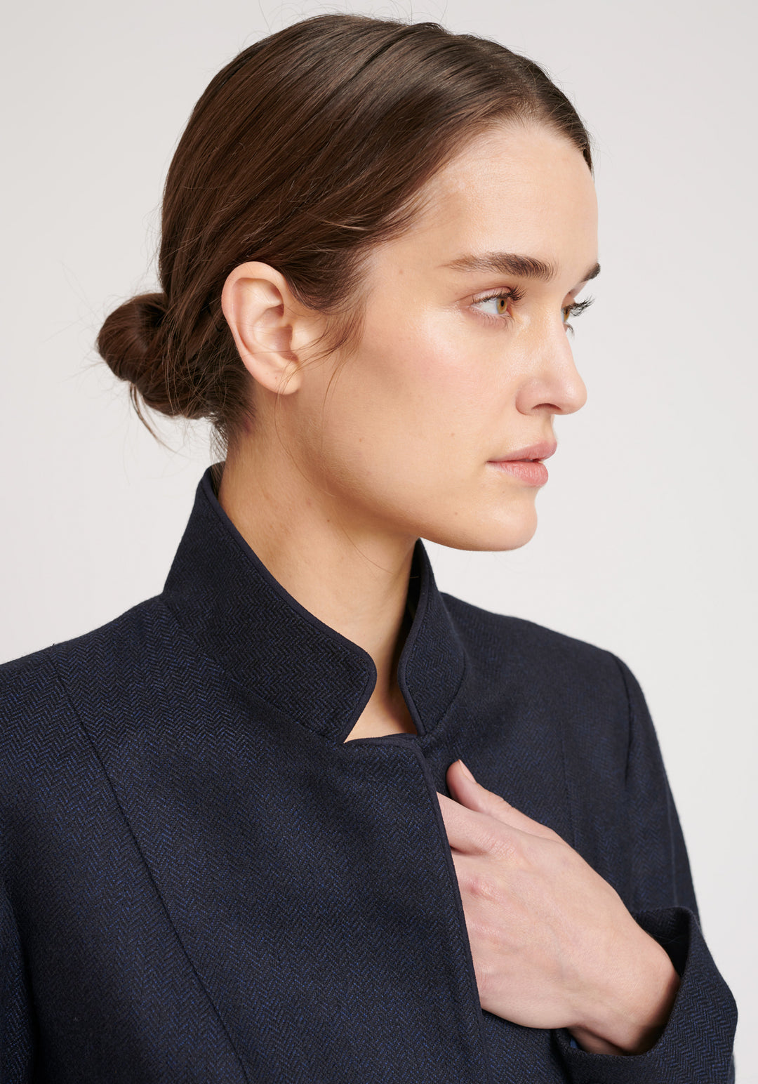 A model wears the Tallulah jacket in a smart navy and black herringbone lambswool. It has a sleek, tailored look, with a single button fastening and suede trimmed collar that can be worn up or down.