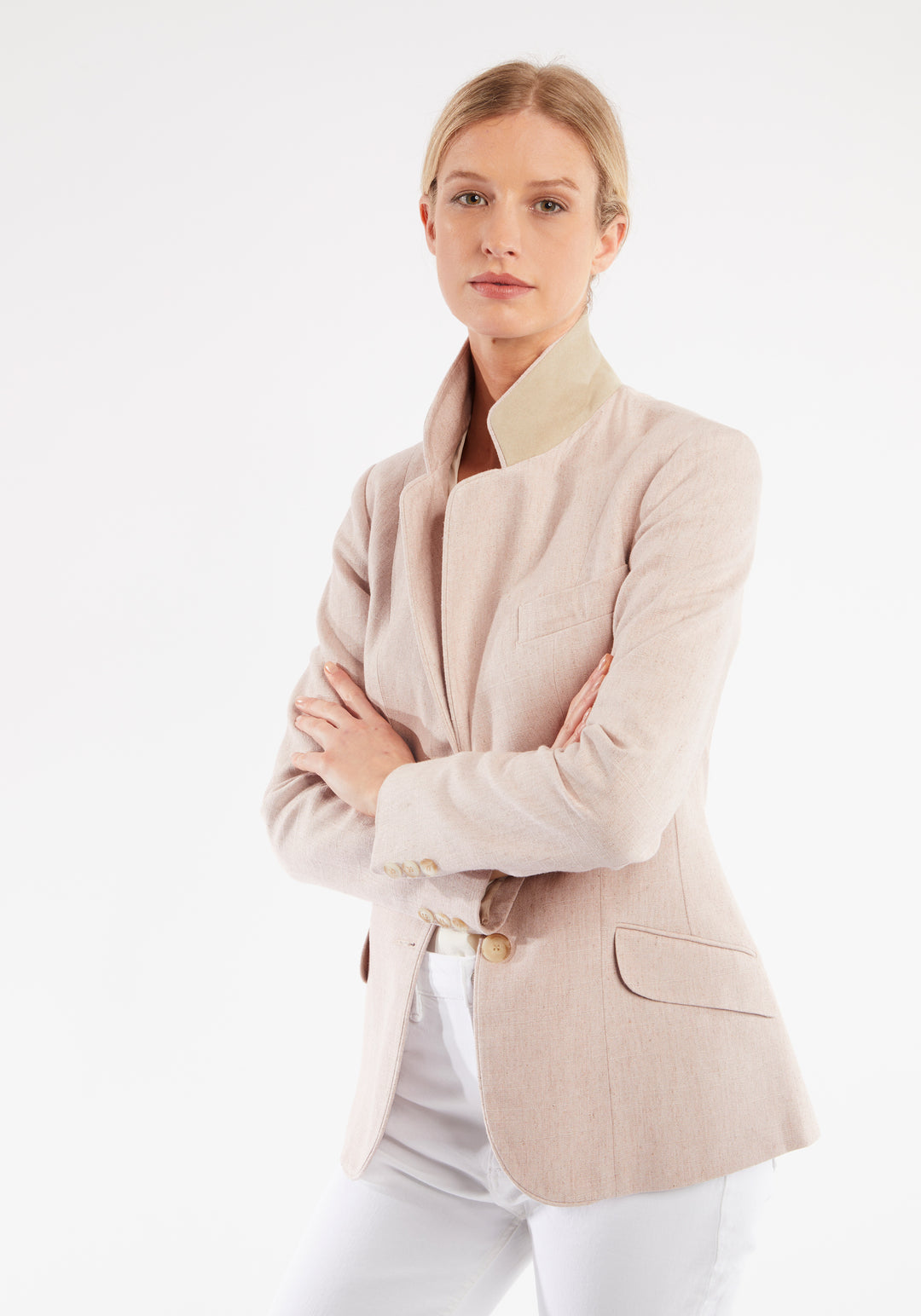Woman wearing light pink jacket with buttons down the front and under collar detailing